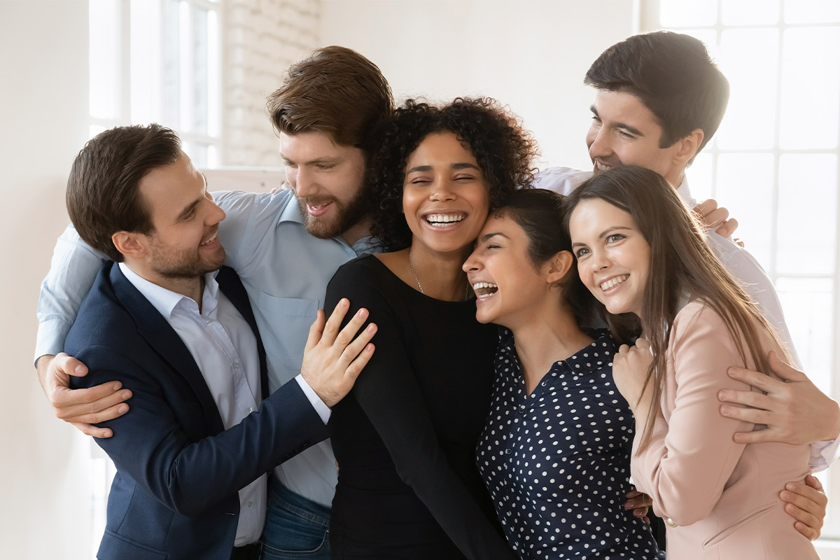Happy business team hugging in an office, marking the end of the year and reflecting on transformative support in 2025.