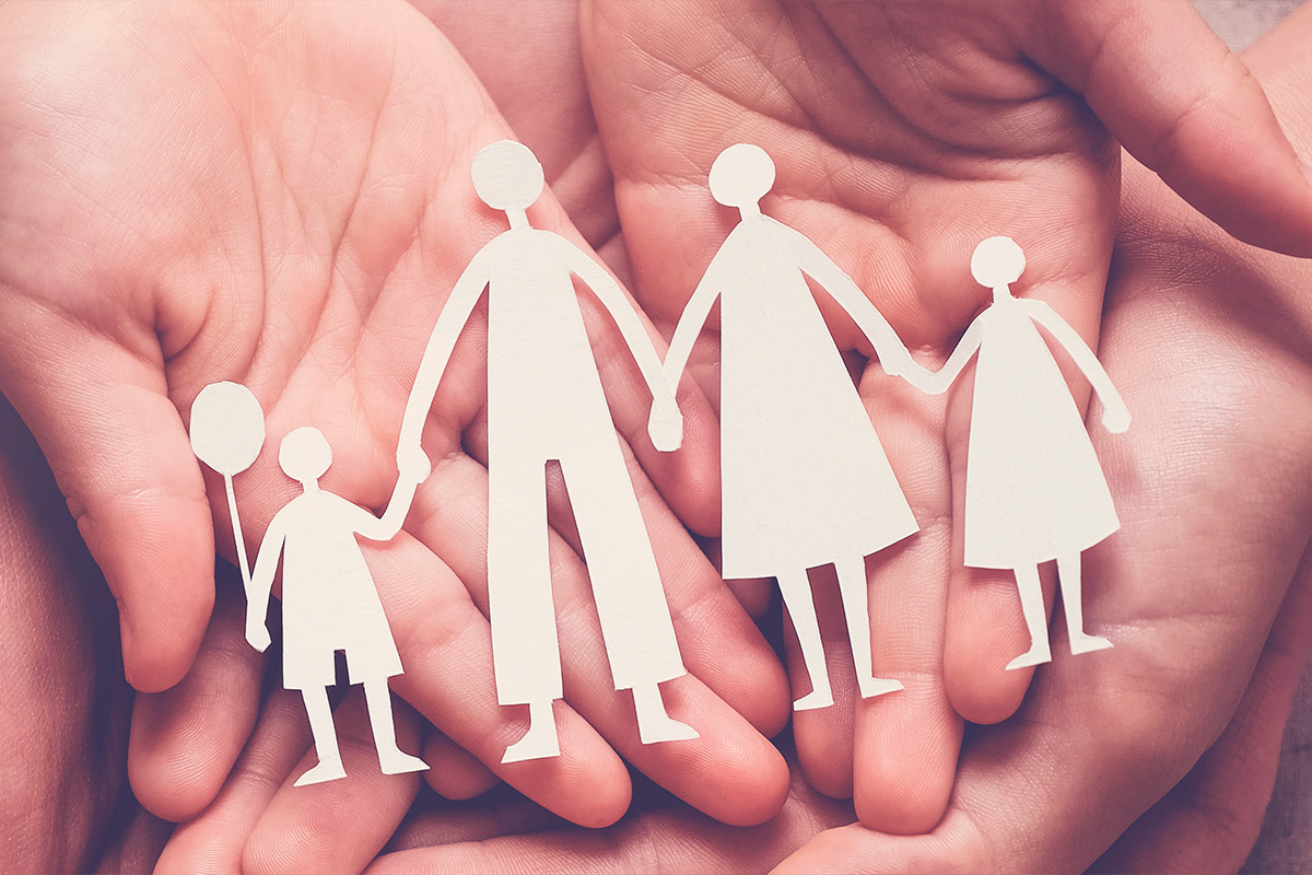 Four family members display paper cutouts of themselves, illustrating unity and support for families overcoming trauma.