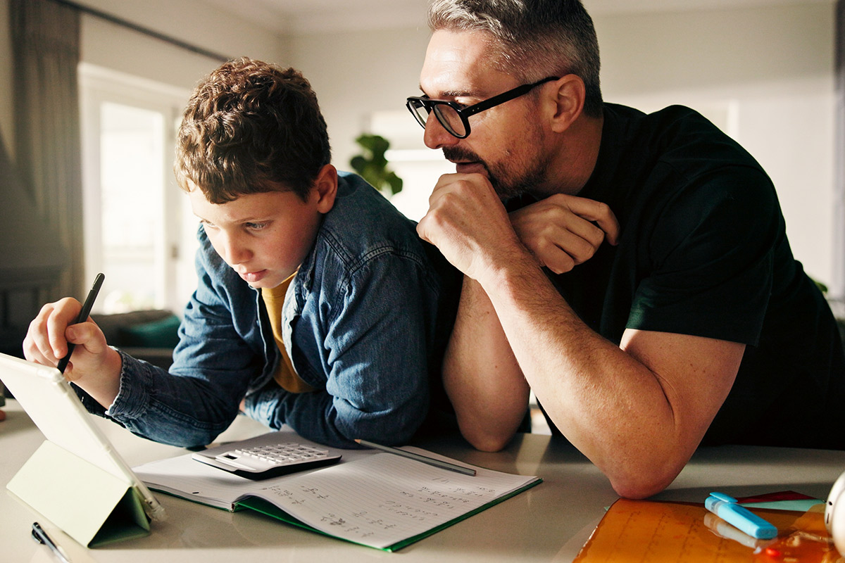 A man and a boy are engaged in a laptop activity, illustrating the importance of co-parenting boundaries in family dynamics.