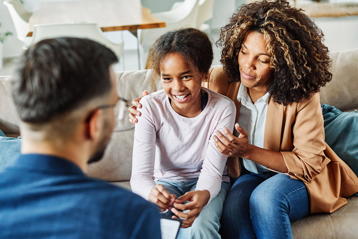 A man and woman sit on a couch with their children, representing new possibilities for healing in the New Year.
