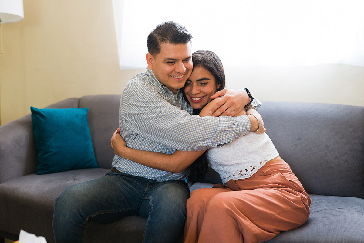 A couple hugs on a couch, representing the healing power of love in overcoming trauma and building healthy relationships.