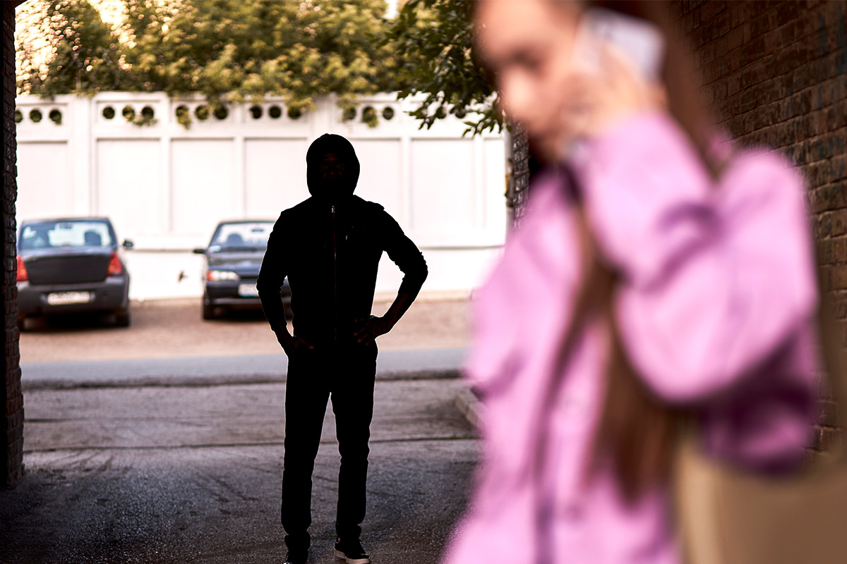 A woman in an alleyway highlights the need for awareness and safety during Stalking Awareness Month.